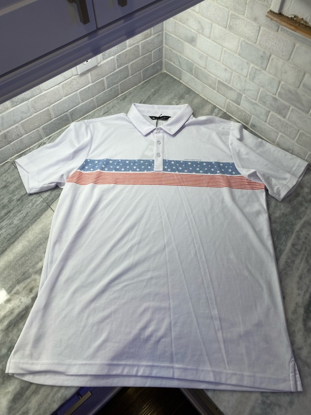 Travis Mathew White Polo with Blue Star Band and Red Stripe Accent